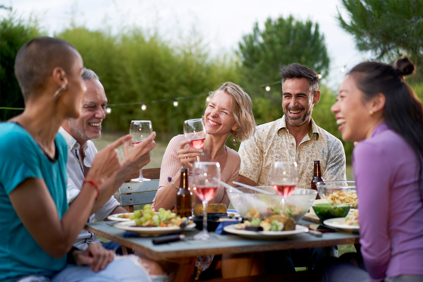Happy middle-aged men and women toasting healthy food at farm house picnic - Life style concept with cheerful friends having fun together on afternoon